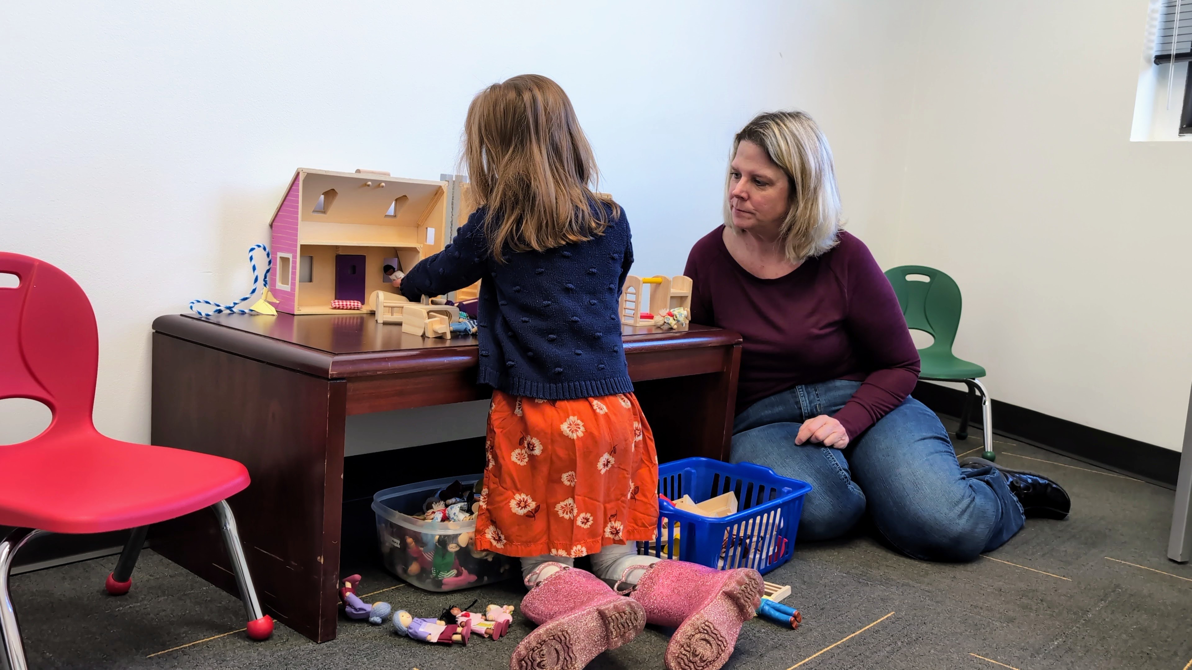 Lynn sitting next to a child playing