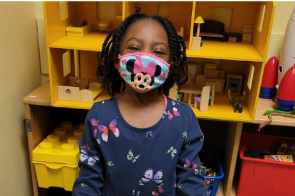 A Primary Project child smiles in the playroom.
